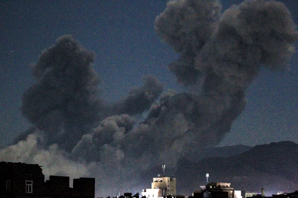 Geceleyin bir dizi binanın arkasında kalın siyah duman bulutları yükseliyor