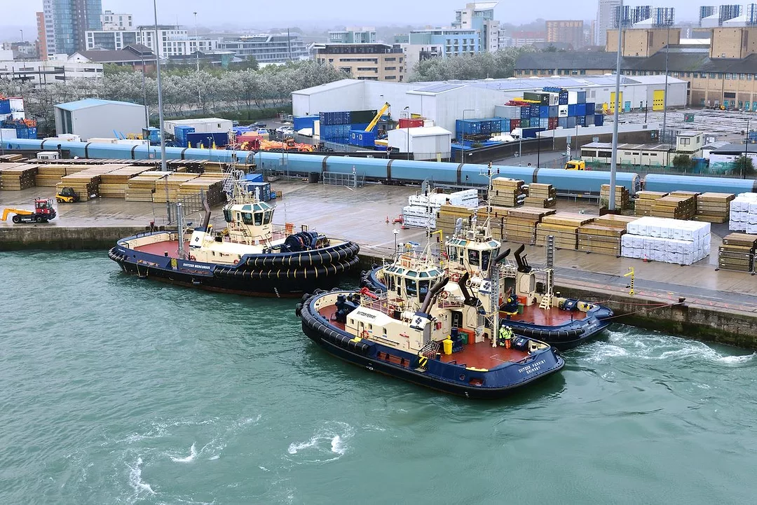 THREE TUG BOATS CLUSTER TOGETHER AT A DOCK