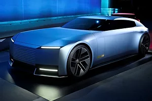 A SLEEK, FANCY CAR GLEAMS UNDER BLUE SHOWROOM LIGHTS
