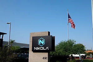 A SIGN OUTSIDE AN OFFICE BLOCK BEARS THE NAME NIKOLA, AN AMERICAN FLAG FLYING BEHIND IT