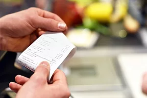 A close-up of hands holding a paper receipt at a store checkout