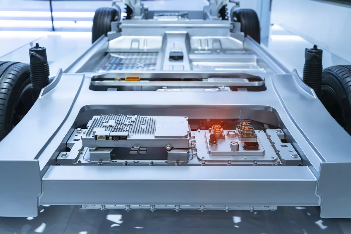 The grey, silver chassis of an unfinished electric vehicle sitting in a white, sterile room