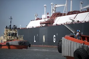 A blue and white container ship docked at a port, with "LNG" written in large white letters across the side