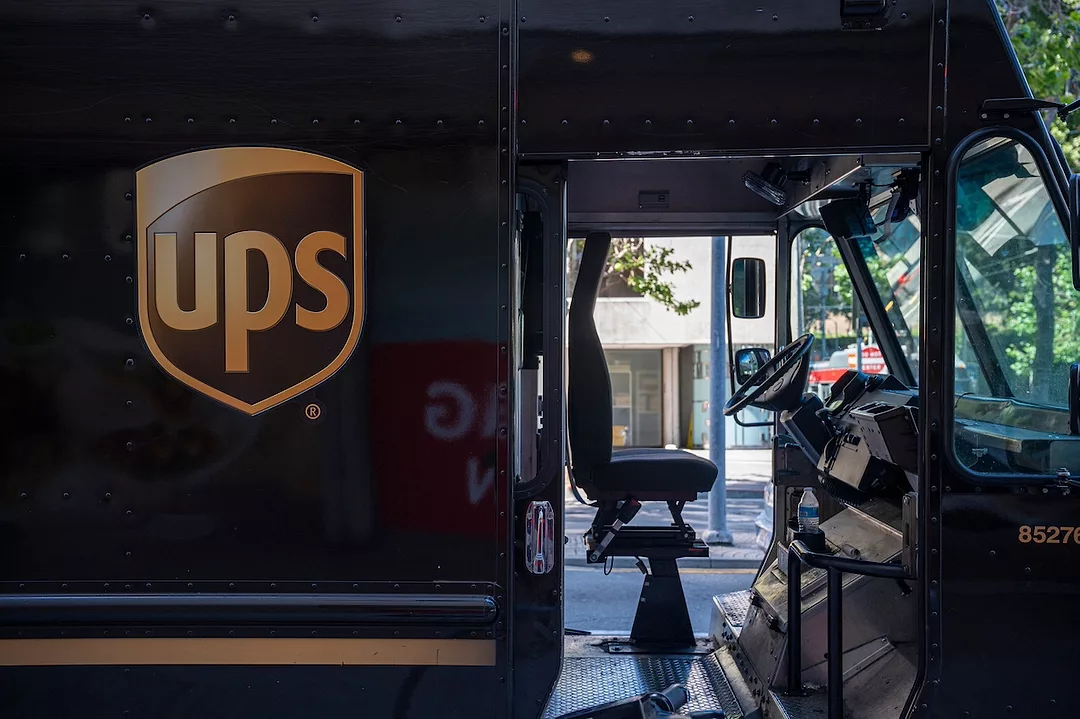A brown delivery truck with "UPS" emblazoned on the passenger side in yellow lettering