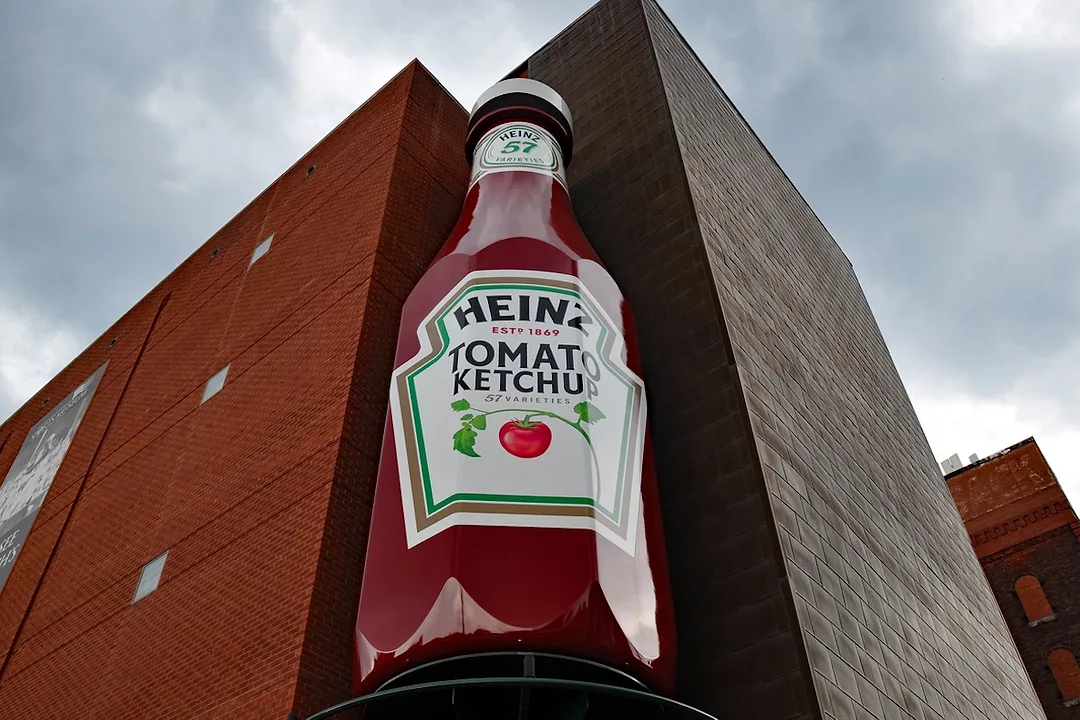 A giant red Heinz ketchup bottle positioned at the corner of a tall red brick building