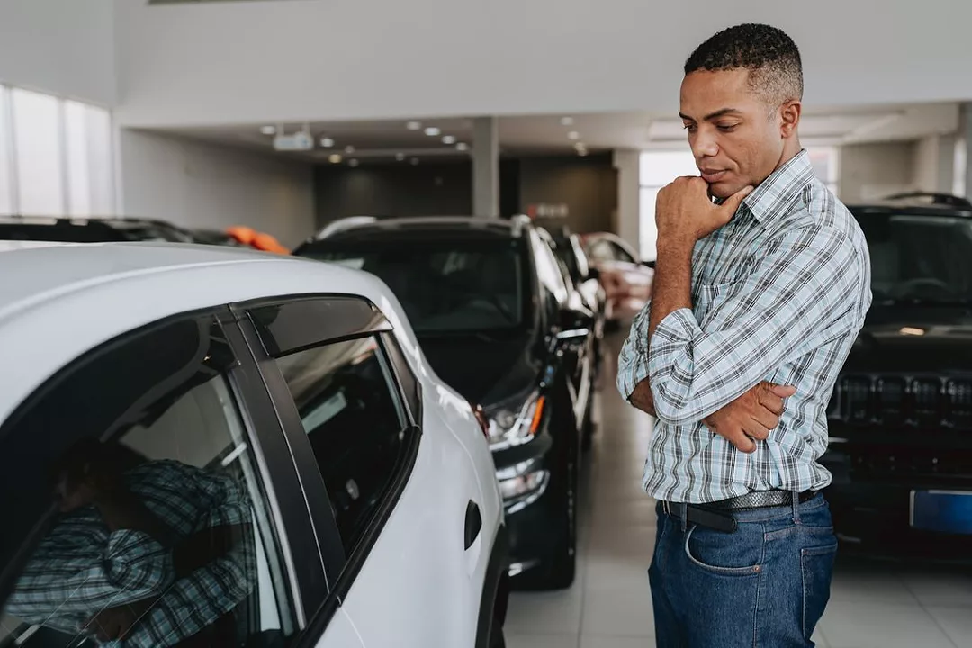 A MAN STROKES HIS CHIN WHILE LOOKING AT AN AUTOMOBILE IN A CAR DEALERSHIPdreswd-1913373628.jpg