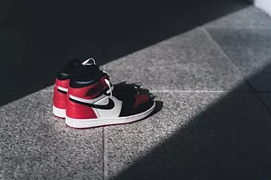 A PAIR OF RED, BLACK AND WHITE SNEAKERS BEAR THE NIKE SWOOSH LOGO