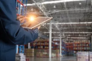 A WORKER IN A WAREHOUSE OPERATES A TABLET COMPUTER