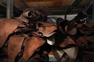 A stack of rolled-up brown leather hides sitting on a shelf