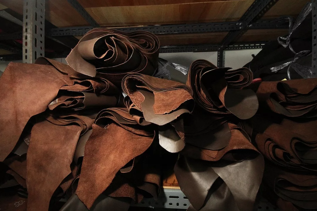 A stack of rolled-up brown leather hides sitting on a shelf