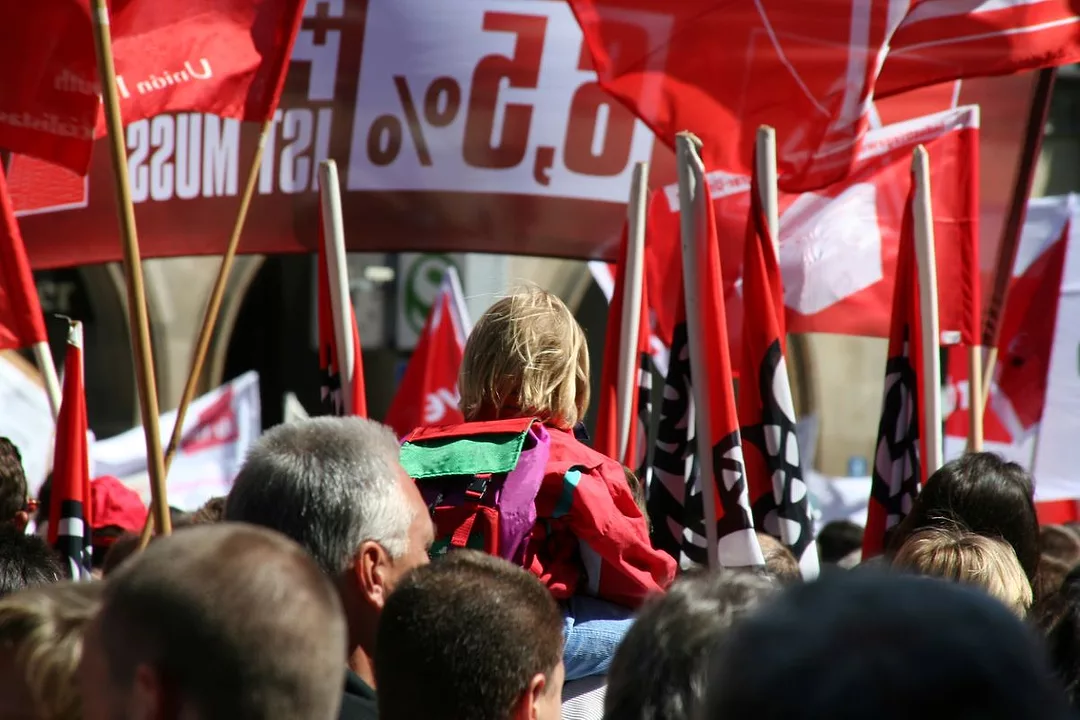 A CROWD OF PROTESTORS HOLD UP RED SIGNS