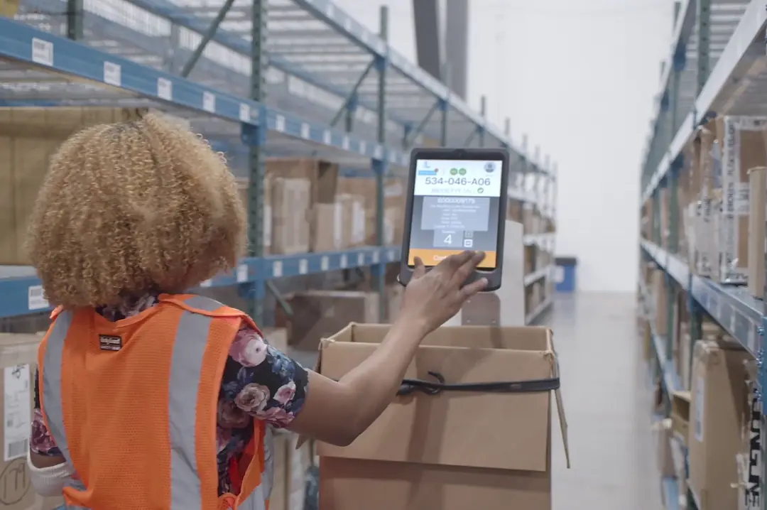 A WORKER IN A WAREHOUSE OPERATES A TOUCH SCREEN