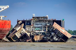 A PARTLY DEMOLISHED SHIP SITS ON A BEACH