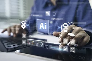 A WORKERS' HANDS ON A COMPUTER KEYBOARD ARE OVERLAID WITH IMAGES OF ARTIFICIAL INTELLIGENCE