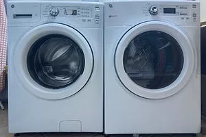 Two front loading white washing machines positioned next to each other