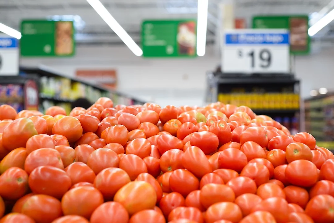 A pile of ripe red tomatoes displayed in a grocery store