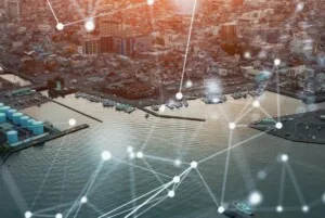 BRIGHT LINES OF LIGHT SUPER-IMPOSED OVER AN AERIAL SHOT OF A PORT INDICATE MOVEMENT OF DATA