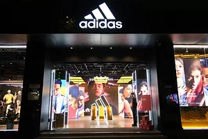 A BRIGHTLY LIT STORE FRONT SPORTS THE ADIDAS LOGO