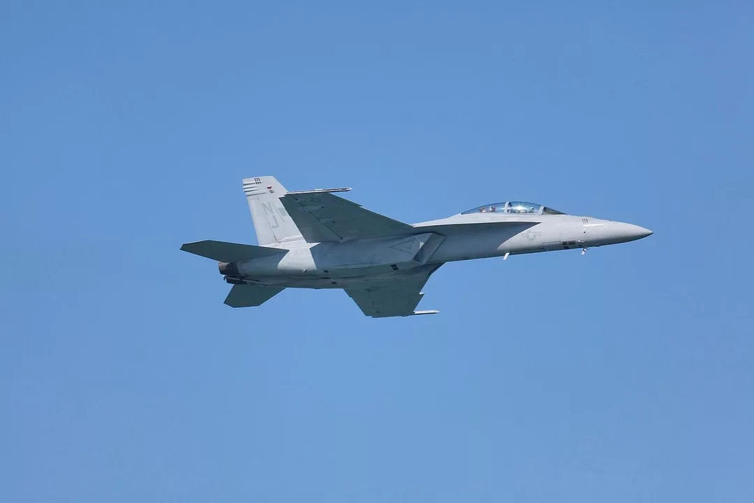 A GREY FIGHTER JET STREAKS ACROSS A CLEAR BLUE SKY