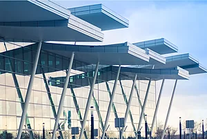 A GLASS FRONTED BUILDING WITH CANTILEVERED OVERHANGING ROOF PANELS