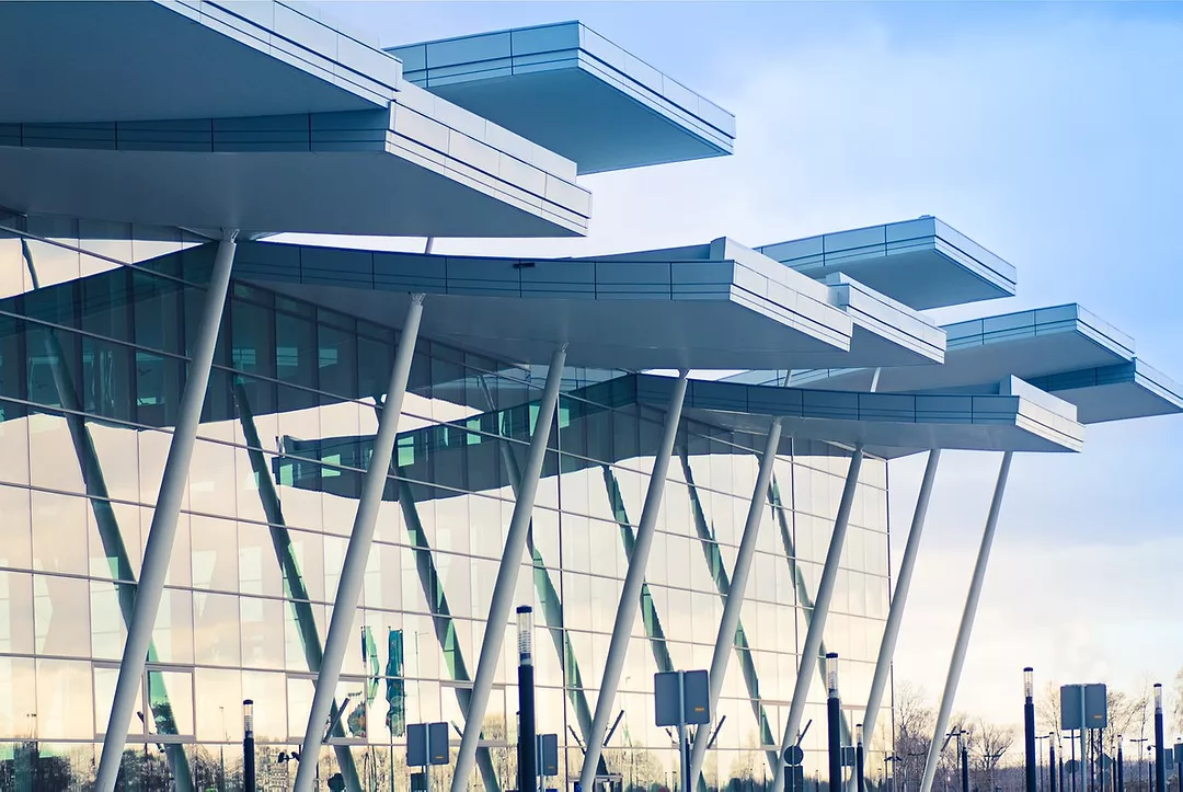 A GLASS FRONTED BUILDING WITH CANTILEVERED OVERHANGING ROOF PANELS