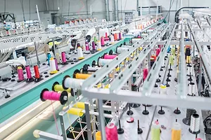 Spools of multi-colored threads arranged along a production line in a white room