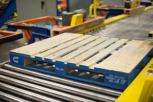 A WOODEN PALLET ROLLS ON A CONVEYOR