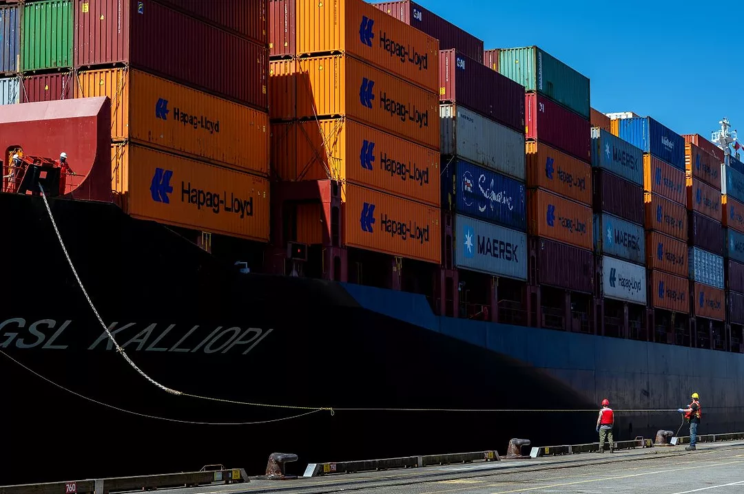 A LARGE SHIP LOADED WITH CONTAINERS SITS BY A DOCK