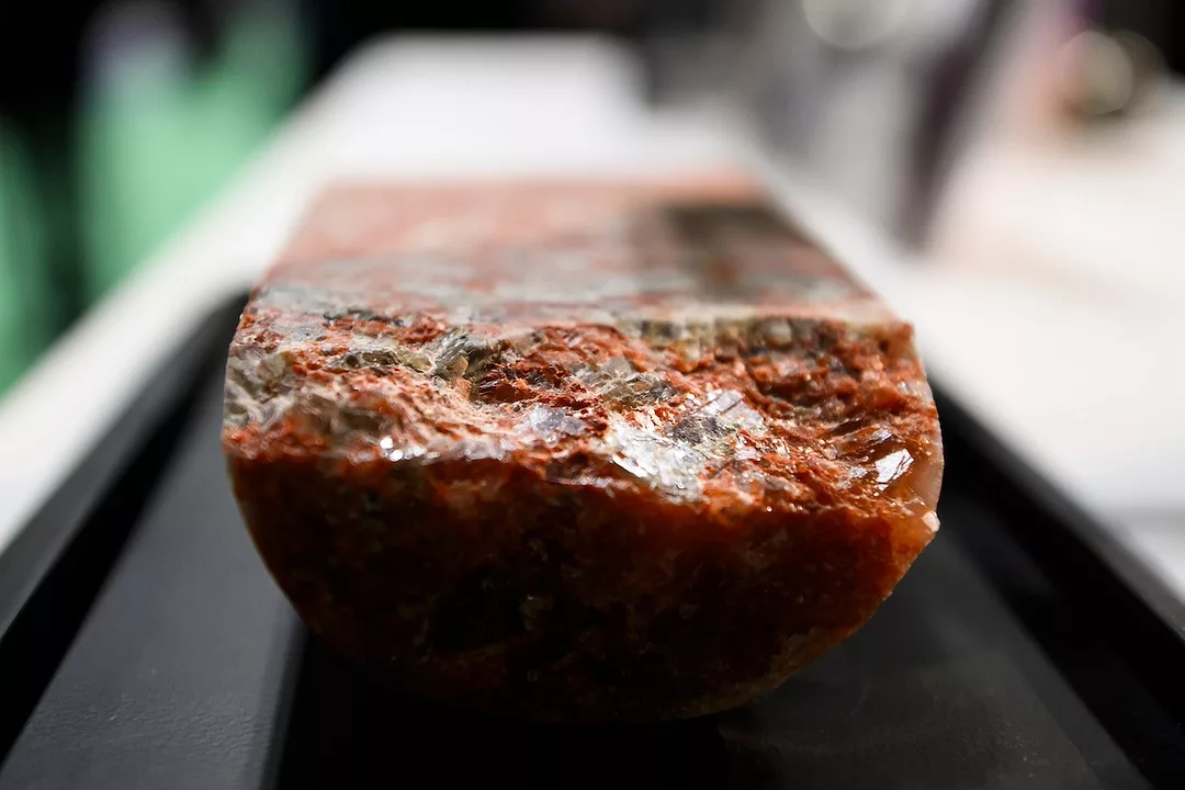 A rectangular slab of red mineral on a black surface