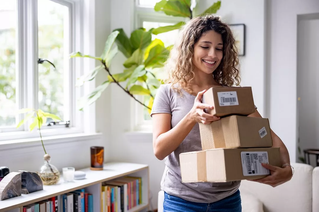 A happy Latin American woman at home receiving packages.