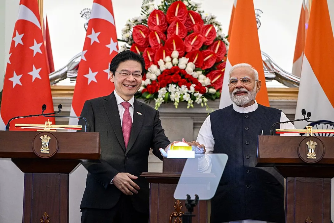 TWO MEN SURROUNDED BY FLAGS ON A PODIUM FACE OUTWARD, SMILING