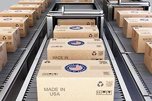 A large group of cardboard shipping boxes featuring Made in USA marks are neatly stacked in a warehouse.