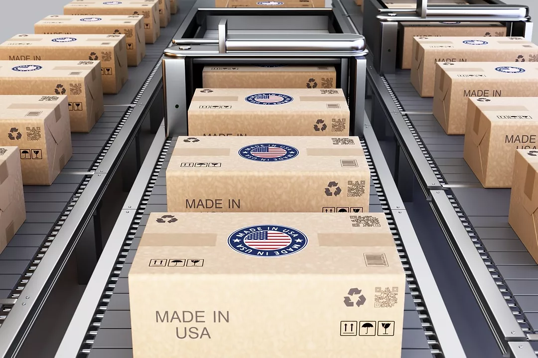 A large group of cardboard shipping boxes featuring Made in USA marks are neatly stacked in a warehouse.