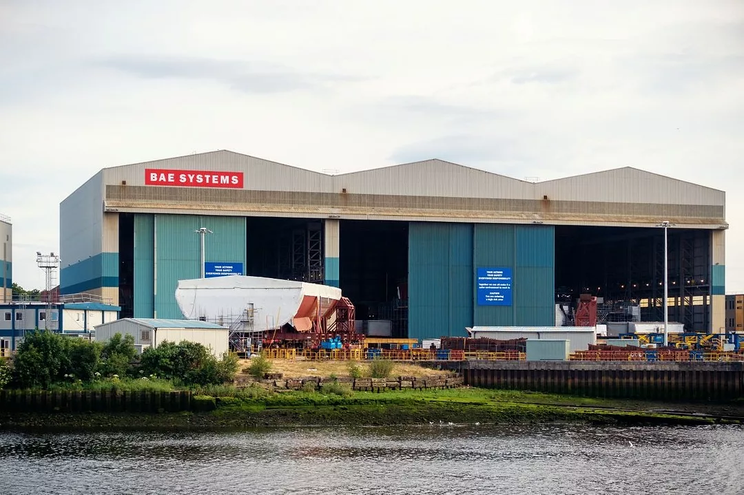 A PICTURE FROM THE WATER OF A BOATYARD, INCLUDING LARGE BUILDINGS