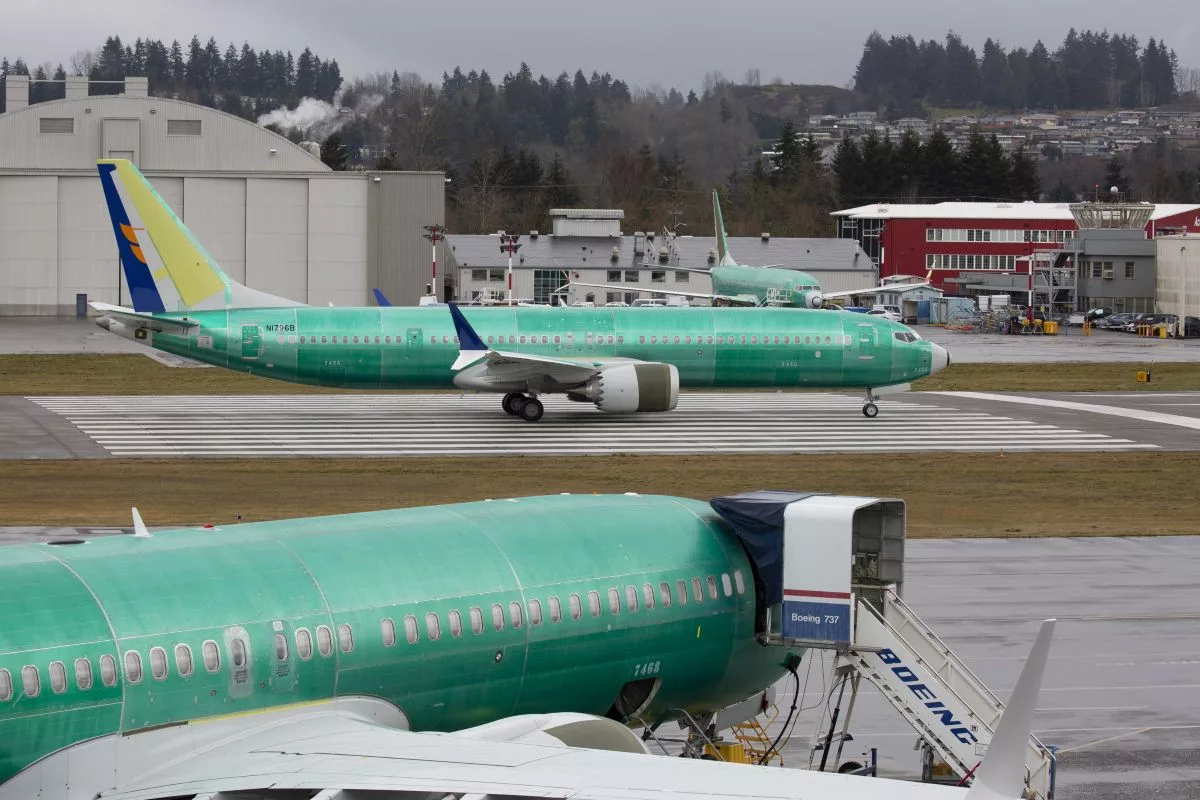 TWO LARGE GREEN AIRPLANES SIT ON THE TARMAC OUTSIDE A HANGAR