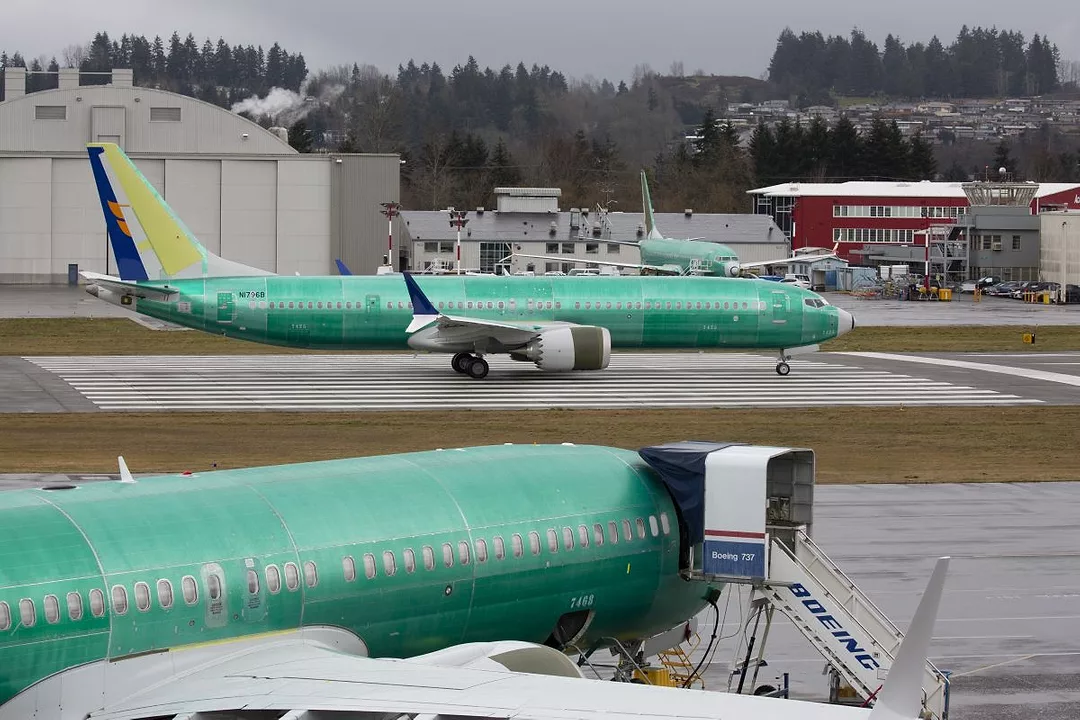 TWO LARGE GREEN AIRPLANES SIT ON THE TARMAC OUTSIDE A HANGAR