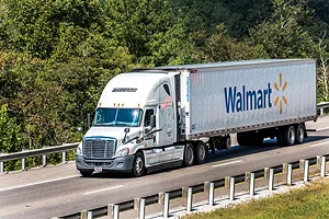 AN EIGHTEEN WHEELER TRUCK BEARING THE WALMART LOGO DRIVES DOWN THE HIGHWAY