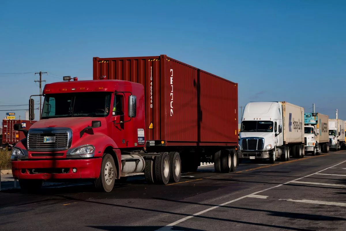 HEAVY DUTY TRUCKS DRIVE IN A LINE DOWN A HIGHWAY