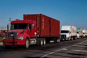 HEAVY DUTY TRUCKS DRIVE IN A LINE DOWN A HIGHWAY