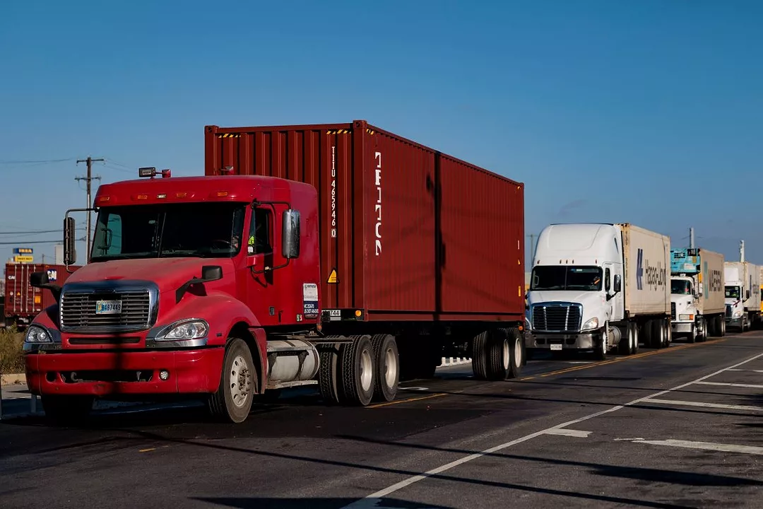 HEAVY DUTY TRUCKS DRIVE IN A LINE DOWN A HIGHWAY
