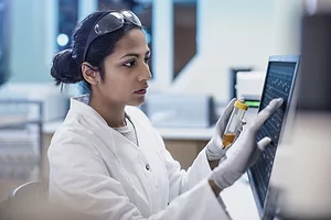 A woman in a white lab coat at a computer