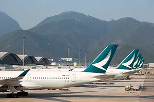 MULTIPLE PLANE TAILS ARE VISIBLE IN A ROW, MOUNTAINS IN THE DISTANCE.