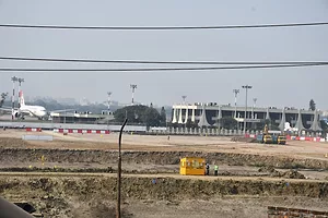 An airport terminal with a white passenger plane to the left, and a white two-story building to the right