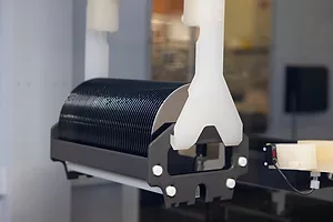 A ROLL OF SHINY BLACK SEMICONDUCTOR MATERIAL UNROLLS FROM A SPOOL