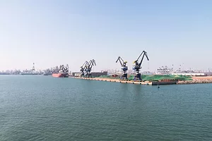 CRANES LINE THE DOCKS OF A PORT ON THE OCEAN