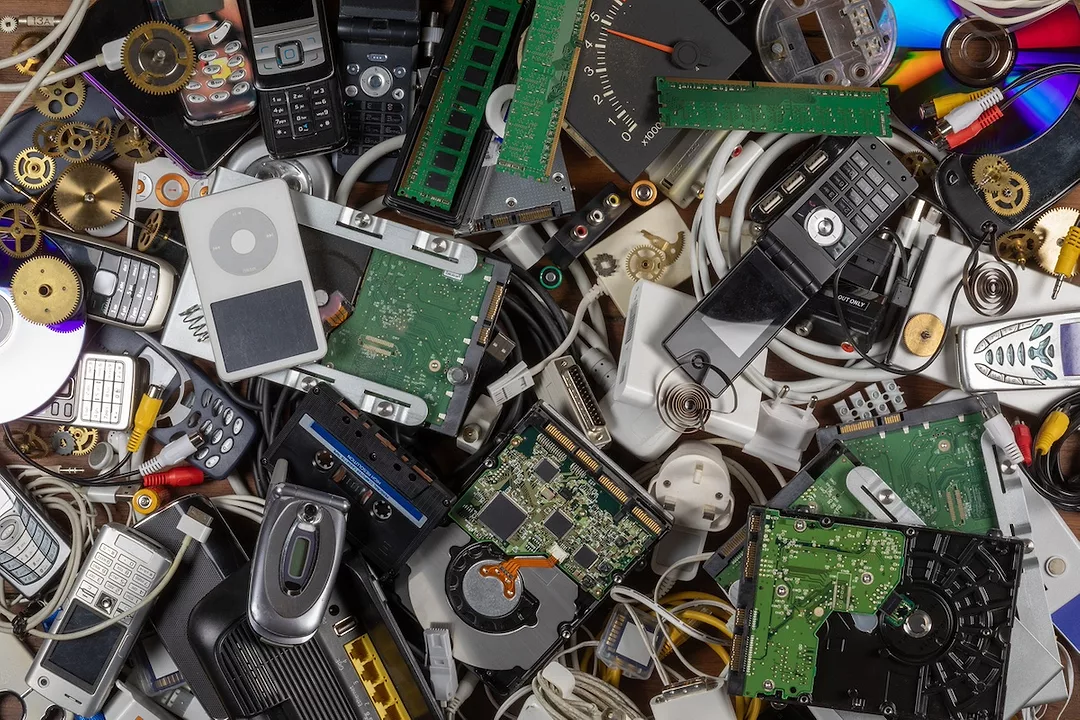 A trash heap of discarded electronics, including cell phones, iPods and computer panels.