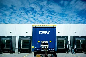 A TRUCK BEARING THE DSV INSIGNIA WAITS AT A LOADING DOCK WITH OTHER TRUCKS