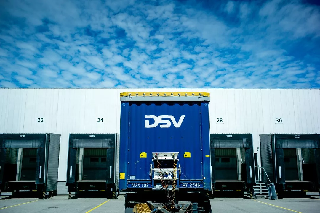 A TRUCK BEARING THE DSV INSIGNIA WAITS AT A LOADING DOCK WITH OTHER TRUCKS