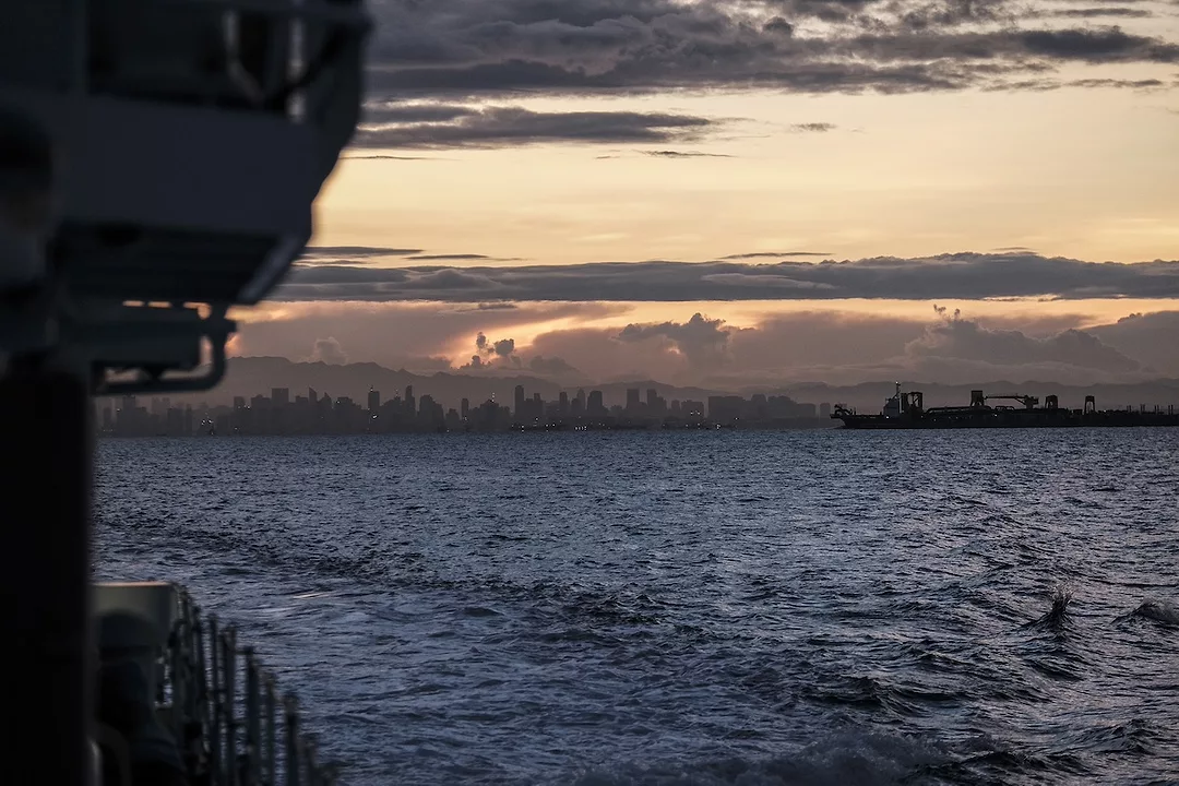 A city skyline at sunset seen from the ocean