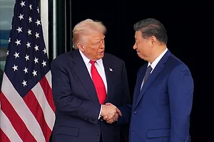 TWO MEN IN BLUE SUITS SHAKE HANDS IN FRONT OF AN AMERICAN FLAG